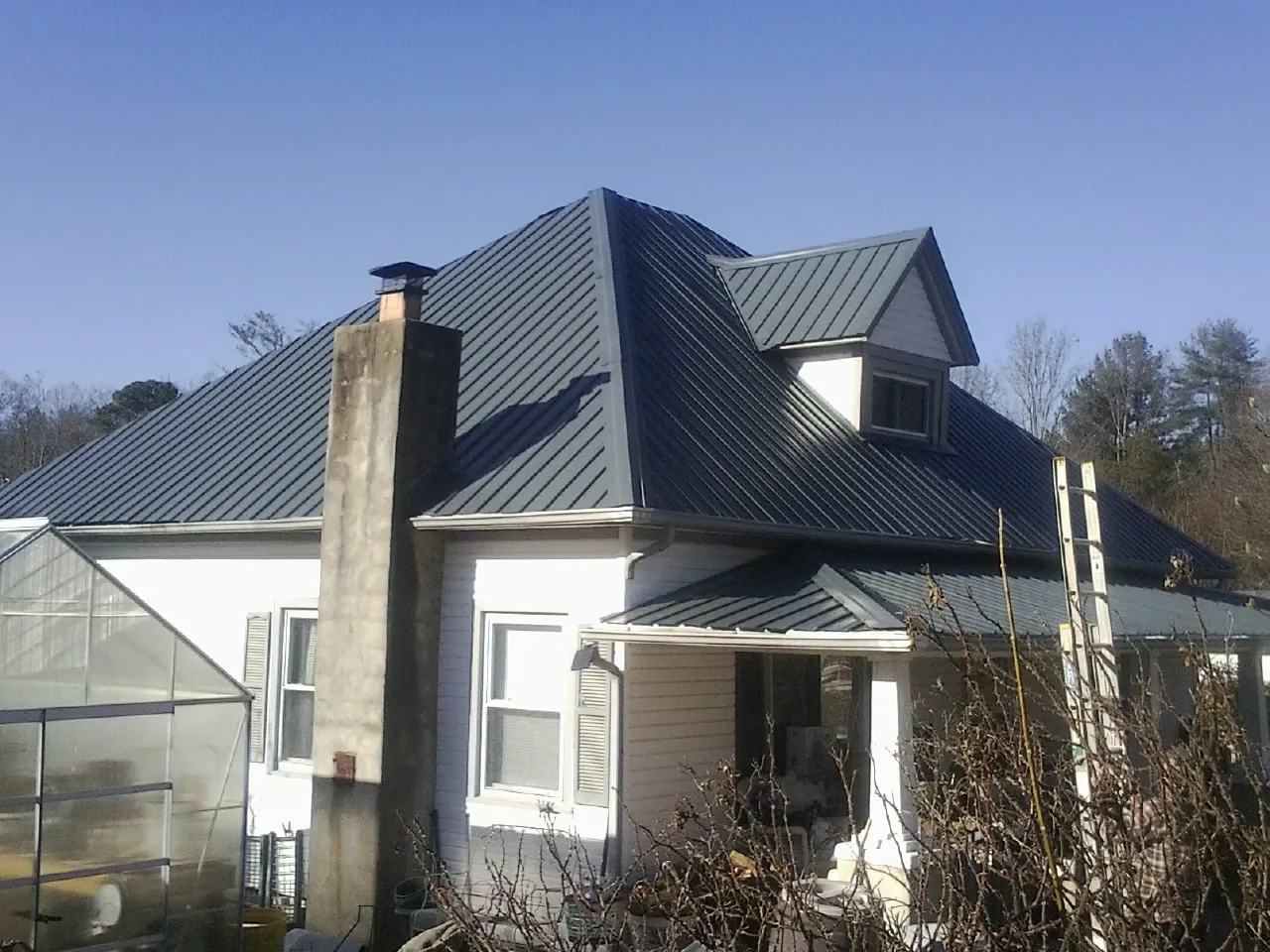 Dark blue standing seam metal roof on a white farmhouse with dormer — Slate & Tile Roof Repair by Roofing Brothers in Sacramento