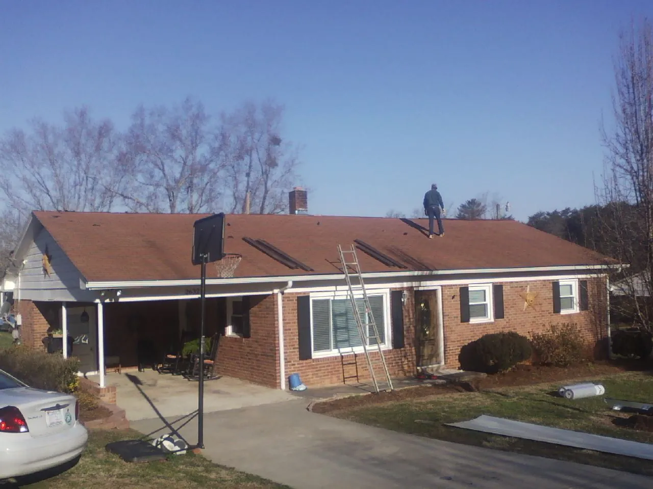 Roofer stripping a shingle roof on a brick ranch before metal panels in Sacramento