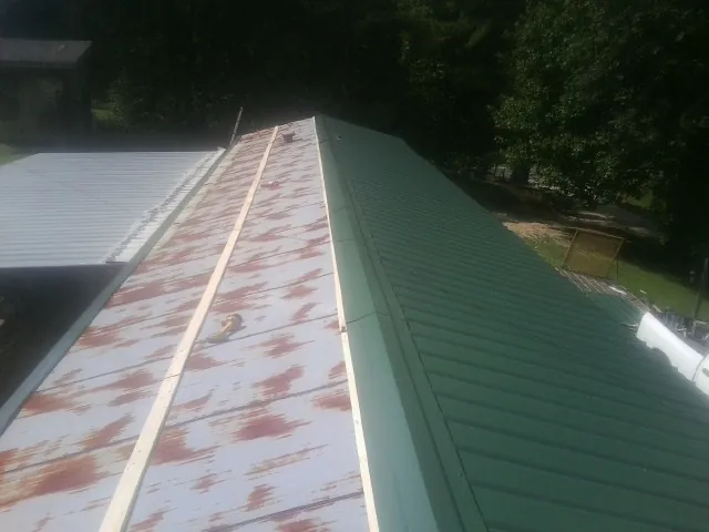 Old rusted panels beside newly installed green metal roofing — Wind Damage Roof Repair by Roofing Brothers in Sacramento