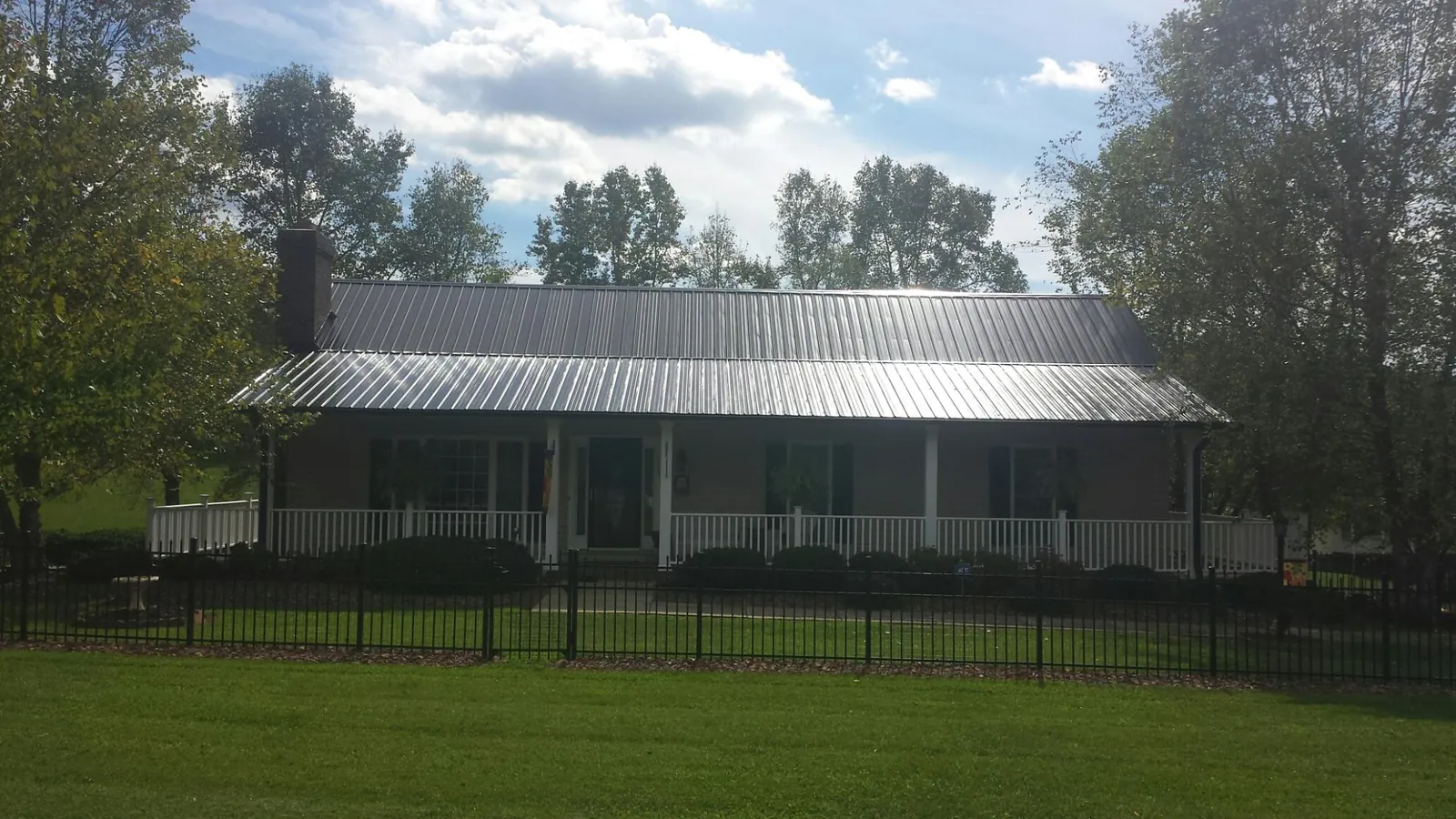 Gray metal roof on a brick ranch with a full width front porch — Gutter Guard Installation work by our crew in Sacramento