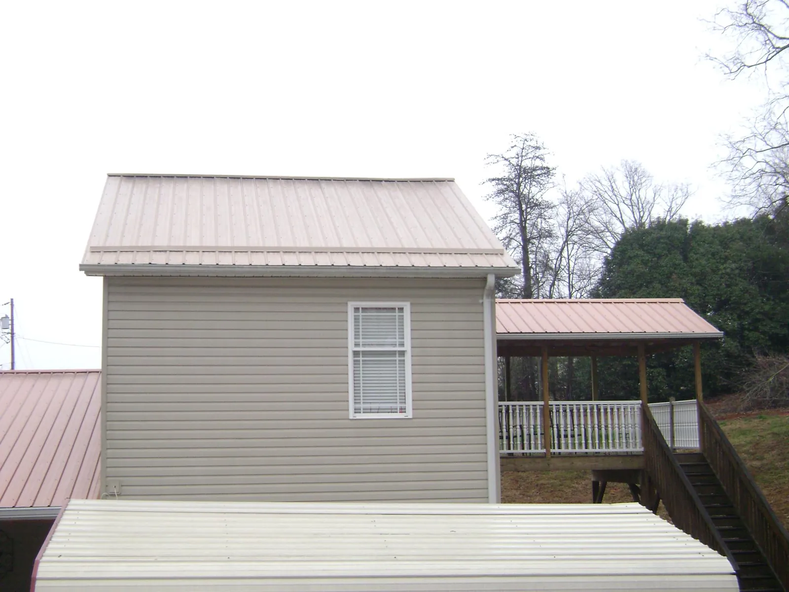 Tan metal roofs on a two story addition and attached porch, from a Roof Replacement job in Sacramento