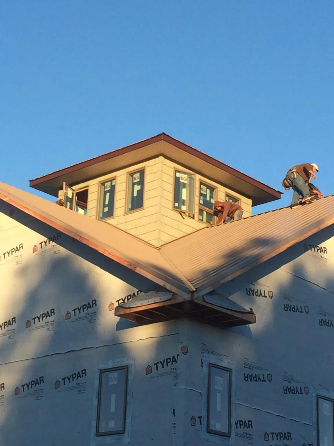 Roofers working around a rooftop cupola on a new metal roof at sunset — Roof Waterproofing in Sacramento by Roofing Brothers